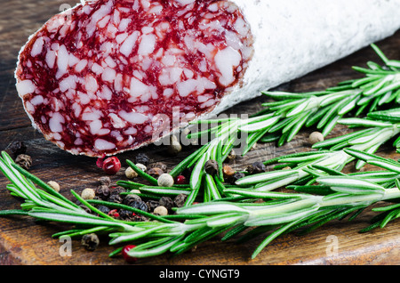 Salami and peper corns with rosemary on cutting board Stock Photo