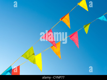 colorful bunting flags against a blue saturated sky Stock Photo