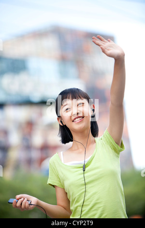 Happy schoolgirl listening to MP3 player and waving Stock Photo
