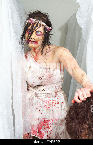 zombie girl holding head while approaching from white curtains Stock Photo