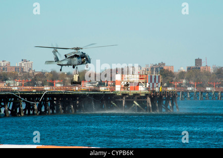 NEW YORK (Nov 6, 2012) A U.S. Navy MH-60S Sea Hawk helicopter assigned to Helicopter Sea Combat Squadron (HSC) 9 sling-loads a power generator from LaGuardia Airport to a platform across a collapsed access bridge. Wasp (LHD 1), USS San Antonio (LPD 17) an Stock Photo