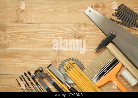 Working tools on a wooden boards background. Including saw, ruler, drill, nails, pliers,hammer, brush,thread,chisel. Stock Photo