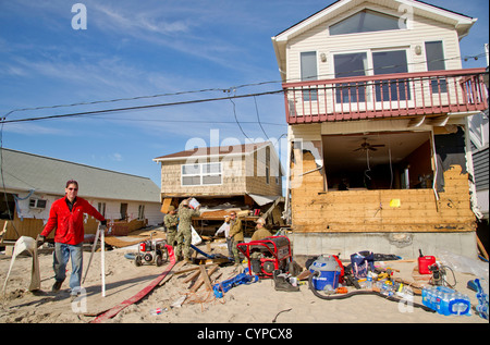 NEW YORK (Nov. 6, 2012) Seabees assigned to Construction Battalion Maintenance Unit (CBMU) 202 and Sailors assigned to Mobile Diving and Salvage Unit (MDSU) 2 work with residents to remove water from their basement that was flooded by Hurricane Sandy duri Stock Photo