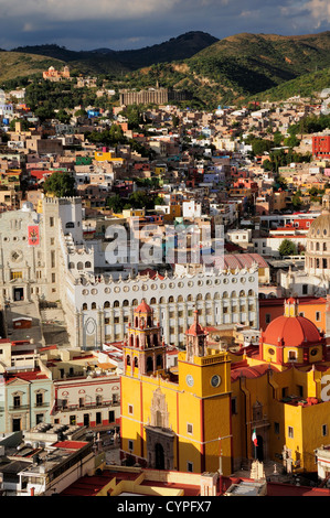 Mexico, Bajio, Guanajuato, Elevated view of colourful Basilica church and university building with barrios on hillside beyond. Stock Photo