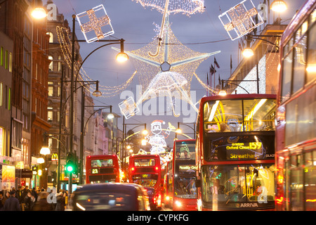 Christmas lights during rush hour at dusk on busy Oxford Street, Oxford Circus, West End, London, England, United Kingdom Stock Photo