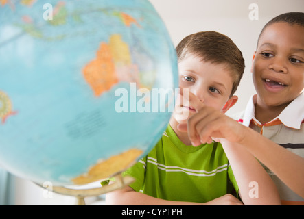 Boys looking at globe together Stock Photo