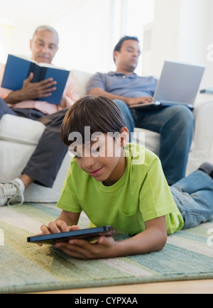 Hispanic boy laying on floor using digital tablet Stock Photo