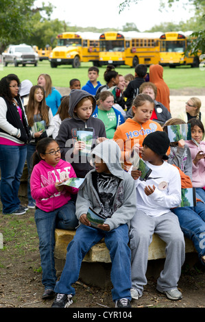 Multicultural group of Texas junior high school students fidget while listening to a speaker on a field trip to Milam County TX Stock Photo
