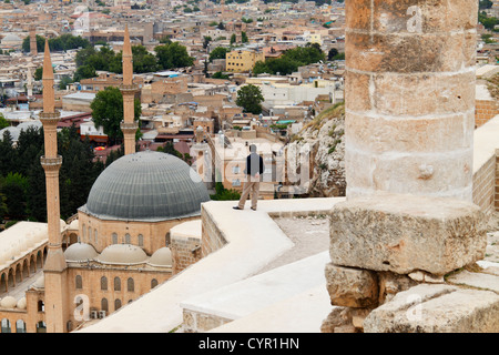 Overview of Urfa city and domes of Mevlid i Halil Camii mosque from the citadel with man staring at the horizon Stock Photo