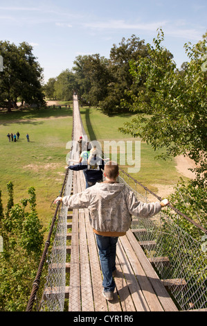 Junior high school students walk across a wood-plank swinging bridge over the San Gabriel River in central Texas Stock Photo