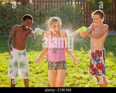 Boys squirting girl with water guns Stock Photo