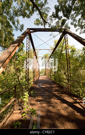 An abandoned one-lane county road and steel truss bridge over the San Gabriel River in central Texas Stock Photo