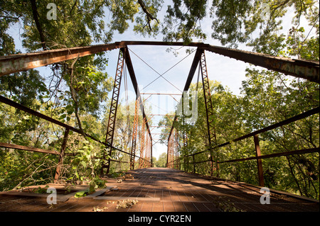 An abandoned one-lane county road and steel truss bridge over the San Gabriel River in central Texas Stock Photo