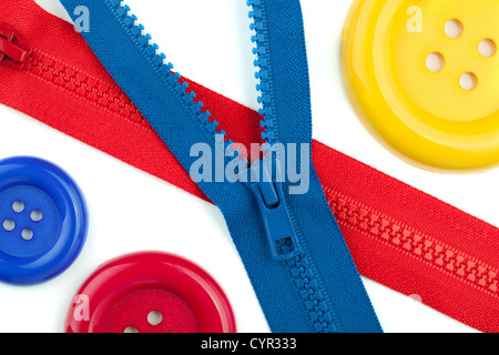 Three colored sewing buttons and two zippers closeup. Isolated on white Stock Photo