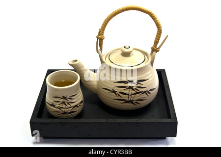 Teapot and teacup painting bamboo leaves on a black tray. Stock Photo