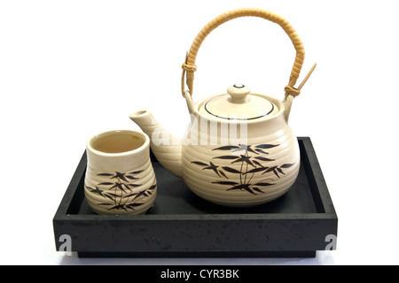 Teapot and teacup painting bamboo leaves on a black tray. Stock Photo