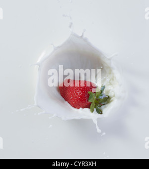 Strawberry dropping into milk Stock Photo