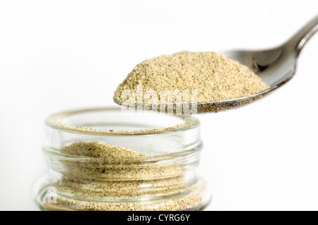 Close up of a spoonful of ground white pepper against a white background held over an open jar Stock Photo