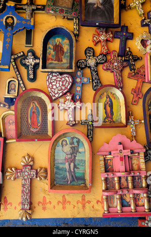 Religious kitsch art displayed on yellow painted wall American  Hispanic Latin America Latino Mexican Religion Shops Shoppers Stock Photo