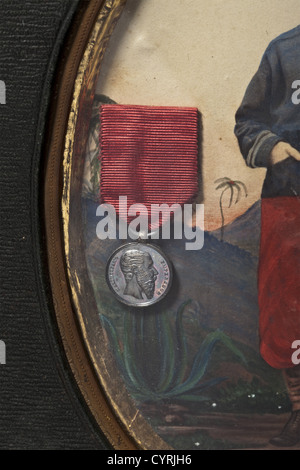 Hand coloured photo and miniature medal,Second Mexican Empire 1864 - 1867 Photo of a member of 'Jäger' Battalion of Austrian Volunteer Brigade in Second Mexican Empire 1864 - 1867.Standing soldier with blue field tunic,red pantaloons,and red field cap with eagle feather in front of a Mexican landscape.Hand coloured with gouache.On left a banded miniature medal of Silver Military Merit Order which Kaiser Maximilian donated to members of expeditionary corps in 1865.Under glass in a green leather frame with stand.Photo ca.10 x 14 c,Additional-Rights-Clearences-Not Available Stock Photo