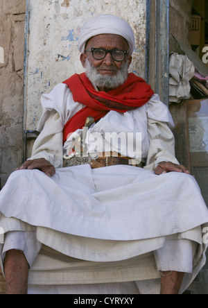 Proud Old Yemeni Man With Glasses And Dagger Sitting In Front Of A Shop, Rada, Yemen Stock Photo