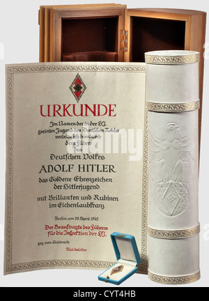 Adolf Hitler,a golden Hitler Youth Honour Badge with brilliants and rubies in an oak leaf wreath Gold(hallmark '585'),platinum,brilliants and rubies. No maker's mark. In a light-blue leather case with white velvet and silk lining. Included is the document tube for the award document,a white leather cylinder with stamped National Eagle above a Hitler Youth emblem and continuous gold-stamped meander bands. The tube is in its corresponding oak wooden casket with brown v historic,historical,1930s,20th century,NS,National Socialism,Nazism,Third Reich,Ge,Additional-Rights-Clearences-Not Available Stock Photo