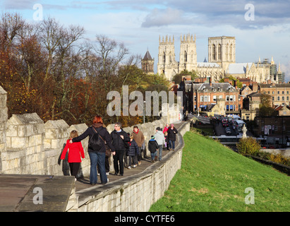 People walking along York City walls with York Minster in the background northern England UK Stock Photo