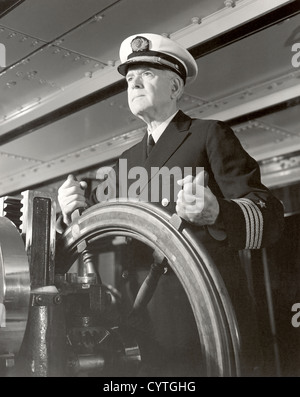 Captain operating ship's steering wheel Stock Photo