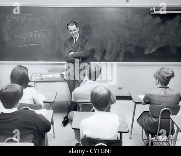 Math teacher talking to students in classroom Stock Photo