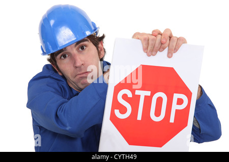 builder in jumpsuit holding stop sign Stock Photo