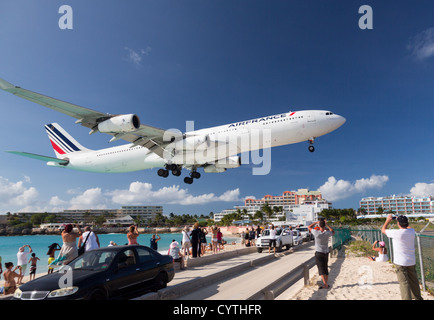 Air France Airbus A340 lands over Maho Beach to Princess Jualiana Airport in St Martin Sint Maarten with tourists watching Stock Photo