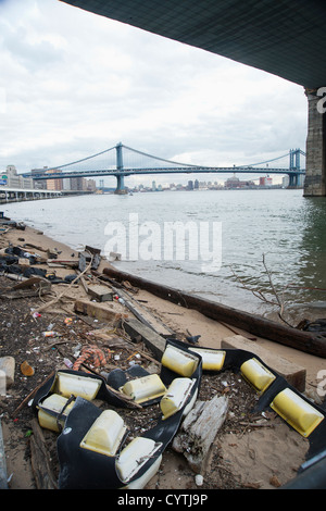 Debris that's washed up on the shore of the East River following the storm surge from Superstorm Sandy under the Brooklyn bridge Stock Photo