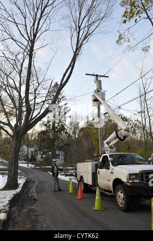 USA, 9 November 2012: Superstorm Sandy Day 11 - Crews from across America lend a hand in beleaguered Westchester County NY. Jimmy Libby (up in bucket) and Ed Lewando of E&E Electrical Inc. came from Boston Massachusetts to help the utility company Con Edison make repairs after Hurricane Sandy. Here, they work on electrical lines on Brevoort Road in Chappaqua New York to restore power to homes that have been without heat and electricity for 11 days. Mr. Lewando says he has never seen so many downed lines and trees in his life. © 2012 Marianne A. Campolongo. Stock Photo