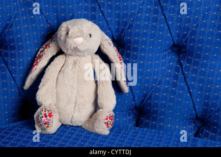 Old childrens toy rabbit on blue regal background Stock Photo