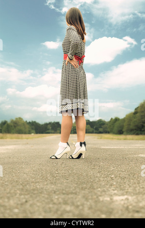 a woman in a black and white dress is standing on a street Stock Photo