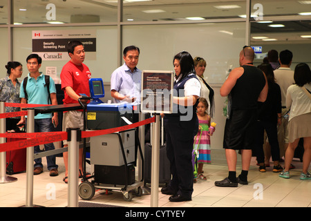 Security officer checking passports of  travelers at Toronto pearson international airport, Canada Stock Photo