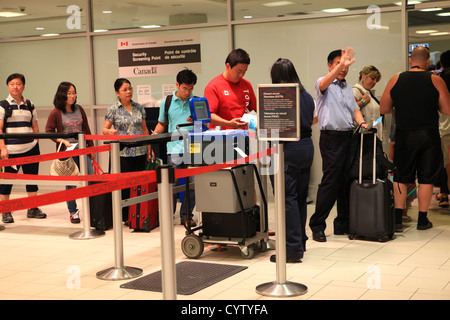 Security officer checking passports of  travelers at Toronto pearson international airport, Canada Stock Photo