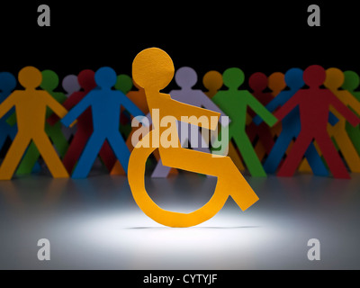 A disable paper figure stands under the spotlight on his wheelchair. Stock Photo