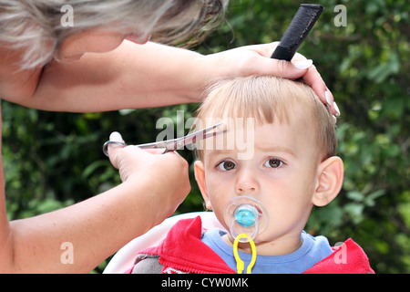 hair cutting first one-year-old child - trimming bangs Stock Photo