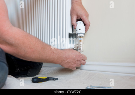 Plumber working to replace a thermostatic radiator valve for domestic clients. Stock Photo