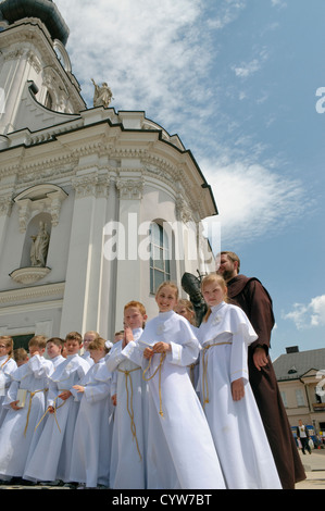 Children and priest on the First Communion Day at the front of parish church in Wadowice, Poland. Stock Photo