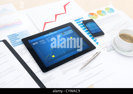 Modern business workplace with stock market data, mobile banking , some charts and graphs on a desk. Stock Photo