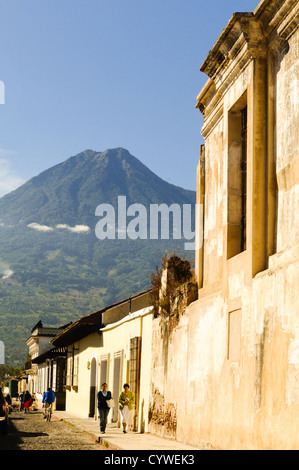 Traditional Spanish colonial architecture of Antigua stands in the foreground, with Volcán de Agua (or Agua Volcano) towering in the background. Famous for its well-preserved Spanish baroque architecture as well as a number of ruins from earthquakes, Antigua Guatemala is a UNESCO World Heritage Site and former capital of Guatemala. Stock Photo