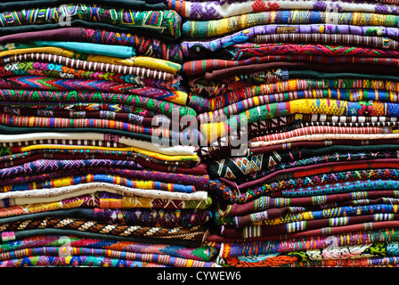 ANTIGUA GUATEMALA, Guatemala — Brightly colored woven textiles are stacked in a market in Antigua Guatemala. Guatemala has a very strong tradition in hand weaving using various types of looms. Famous for its well-preserved Spanish baroque architecture as well as a number of ruins from earthquakes, Antigua Guatemala is a UNESCO World Heritage Site and former capital of Guatemala. Stock Photo