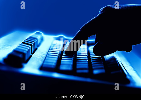 conceptual finger poised on computer keyboard Stock Photo