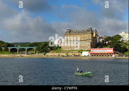 A man fishing in a rowing boat with the grand hotel in the background south bay scarborough north yorkshire england uk Stock Photo