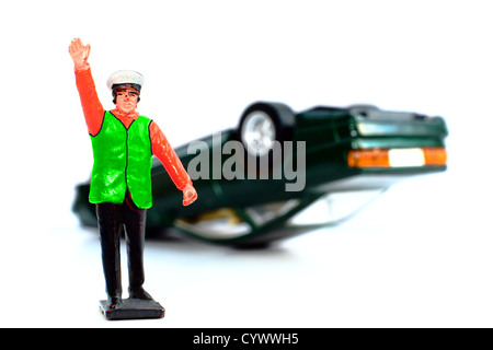 A toy policeman in front of an overturned toy car. Isolated on a white background. Stock Photo