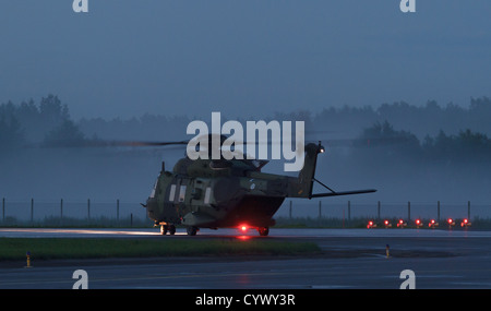 Finnish Army NH-90 helicopter preparing for take-off at midsummer midnight in foggy weather. Stock Photo