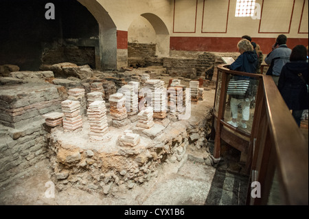 Roman Baths Caldarium Tiled Towers Ancient Roman Heating System Bath England | BATH, United Kingdom — The caldarium, or hot room, of the Roman Baths in Bath features the remains of its ancient hypocaust heating system. These pillars, known as pilae, were part of the sophisticated underfloor heating method used to warm the baths: hot air from a furnace circulated beneath the raised floor, heating the room above. The Roman Baths, a well-preserved ancient site known to the Romans as Aquae Sulis, are a major historical attraction in Bath. This UNESCO World Heritage Site showcases Roman engineering Stock Photo