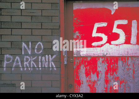 No Parking Sign written on a Brick Wall with Street Address in Red and White Stock Photo